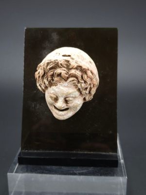 un gros plan d'une sculpture représentant une tête de femme posée sur un socle noir