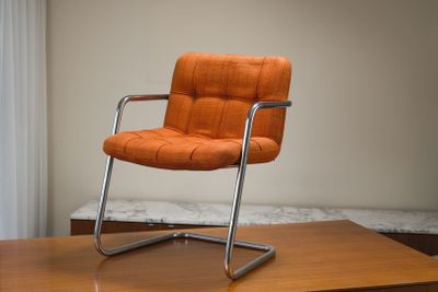 une chaise orange posée sur une table en bois