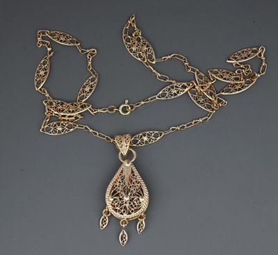 a close up of a gold necklace with a chain attached to it
