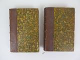 two old books sitting on top of each other on a white surface