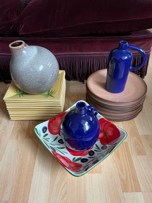 a blue vase sitting on a plate next to a blue vase on a wooden floor
