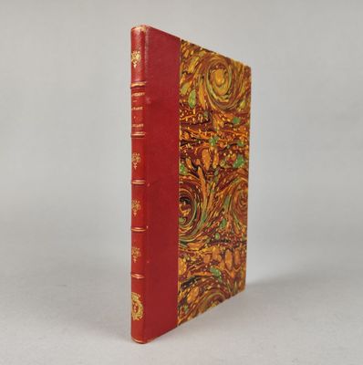 un vieux livre à la couverture rouge posé sur une surface blanche