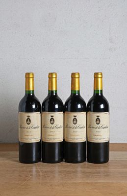 quatre bouteilles de vin sont alignées sur une table en bois