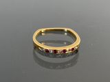 a gold ring with red and white stones on a black surface