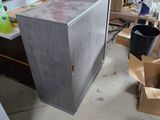 une armoire métallique au milieu d'une pièce, avec des cartons posés par terre