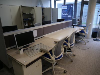 une image représentant un bureau cloisonné avec deux ordinateurs et un clavier