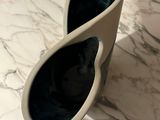 a white vase that has a pair of sunglasses on it