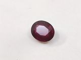 a close up of a red ruby stone on a white surface