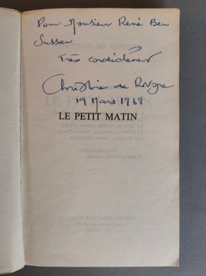 un livre ouvert, sur lequel est posée une note manuscrite, posé sur une table