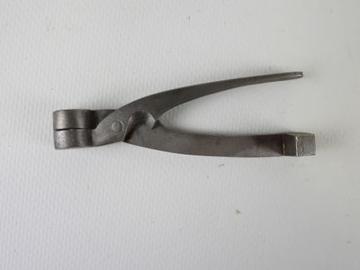 une pince métallique posée sur une surface blanche
