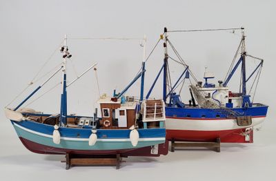 two model fishing boats on display on a white surface