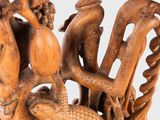 carved wooden sculpture of a dragon and a snake with a human hand