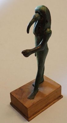 une statue représentant une femme tenant un oiseau, posée sur un socle en bois