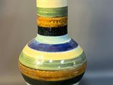 a multicolored vase sitting on a gray surface