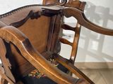 a wooden chair that has a black seat on it