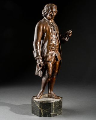 a bronze statue of a man holding a glass of wine