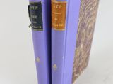 deux livres violets posés l'un sur l'autre sur une surface blanche