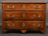 une commode ancienne dont les tiroirs sont ornés de ferrures en laiton