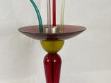 un vase rouge et vert posé sur un socle et muni d'un fil métallique