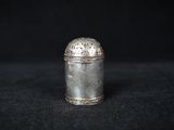 an old silver container sitting on top of a black surface