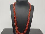 a red coral necklace on a black mannequin