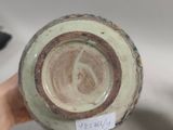 a person holding a vase with a tag on it