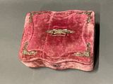 a red velvet box with a gold ring on top of it