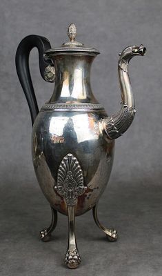 une théière en argent avec une anse en forme de paon, posée sur un socle
