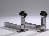pair of metal brackets on a white surface with a gray background