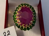 une image représentant une bague verte et rose dans une boîte rouge