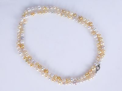 un gros plan d'un collier de perles blanches et jaunes posé sur une surface blanche