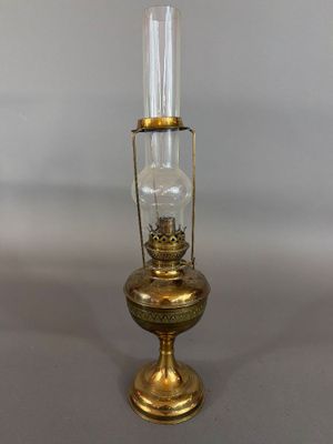 une lampe à huile ancienne en laiton, dotée d'un cylindre en verre et posée sur un socle