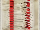 six forks in a box with red ribbon on them