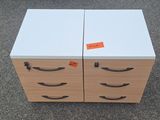 two white drawers with black handles on each side of them
