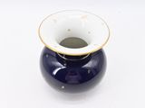 a small blue vase with a gold rim on a white surface