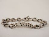 a close up of a silver bracelet on a white surface