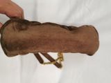 a person holding a brown bag with a gold chain around it