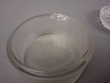 a glass of water sitting on a table next to a plastic container