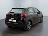 the back of a black car is parked in a large room