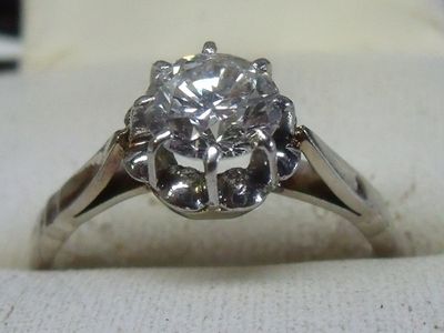 une photo d'une bague en diamant posée sur un tissu blanc
