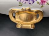 a gold teapot sitting on a table next to a white vase