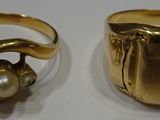 two gold rings and a pearl ring on a white surface