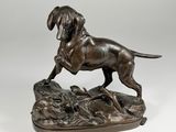 a bronze statue of a dog on a rock with a bird in its mouth