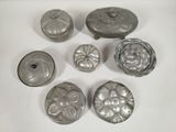 several silver metal knobs and covers on a white surface