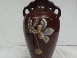 a brown vase with flowers on it on a white table