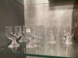 Plusieurs verres à vin vides sont posés sur une étagère en verre dans une pièce.