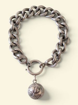 bracelet à chaîne en argent orné d'une breloque en forme de boule en argent sur fond blanc