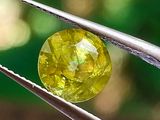 un gros plan d'un diamant jaune tenu par une paire de pinces