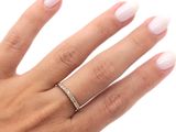La femme tient à la main une bague en diamant qu'elle porte au doigt.