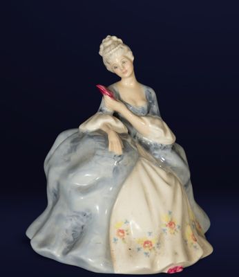 a figurine of a woman sitting on a chair